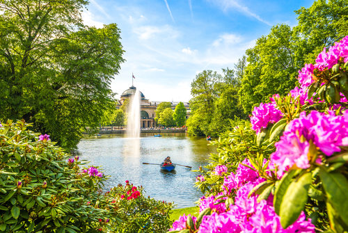 Kurpark mit Blick über Kurparkweiher zum Kurhaus unter strahlend blauem Himmel