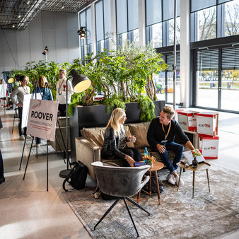 Menschen sitzen auf dem Sofa in der Messehalle und unterhalten sich