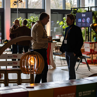 Menschen stehen in der Messehalle und unterhalten sich