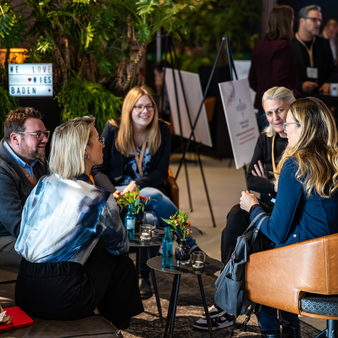 Menschen sitzen in der Messehalle und unterhalten sich